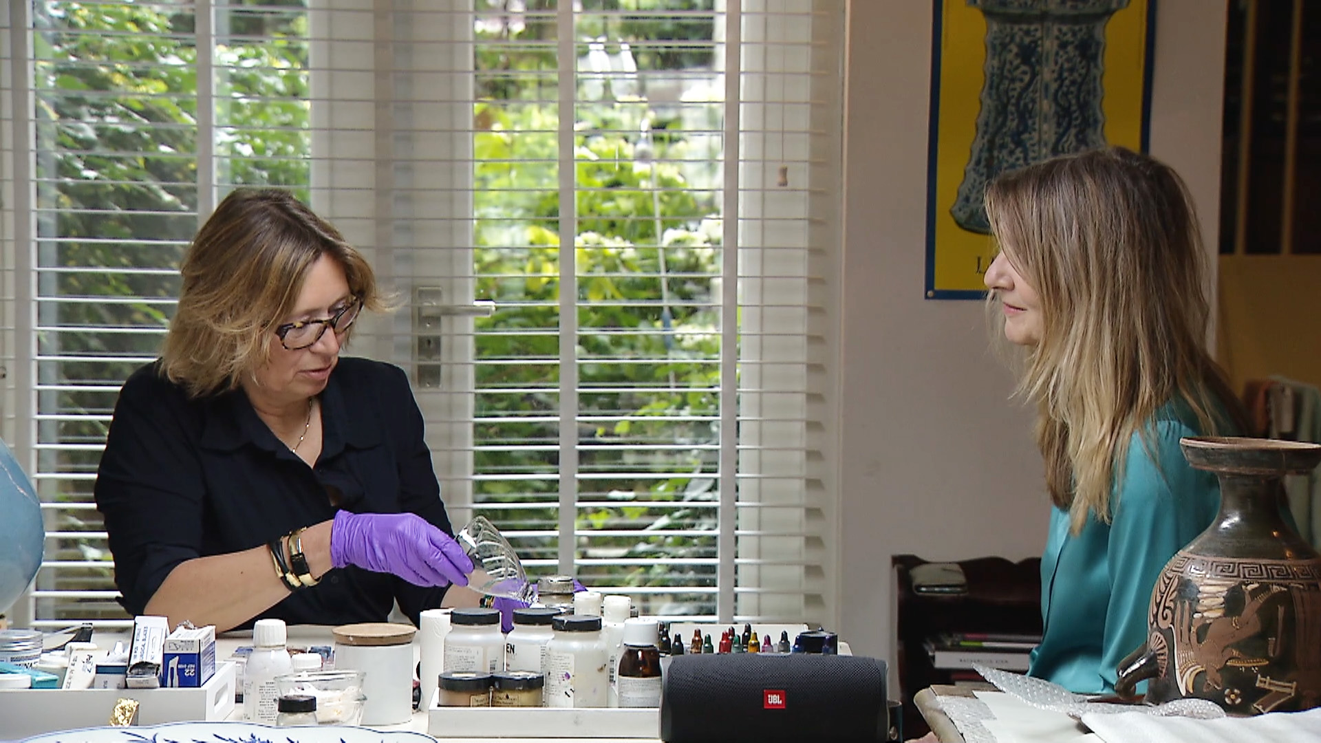 Expert Anna Laméris zit aan tafel bij restaurator Sabine Westerhuis die bezig is met een glas